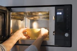 Woman at home heating food in microwave oven
